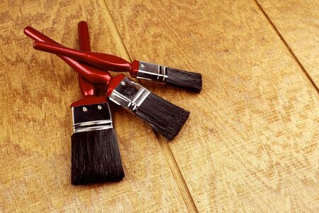 Three paintbrushes on wooden surface