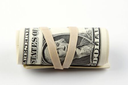 Roll of U.S. banknotes rolled up on plain backgroundの写真素材