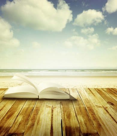 Open book on deck in front of beach sceneの写真素材