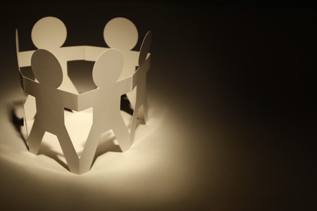 Team of paper doll people holding handsの写真素材