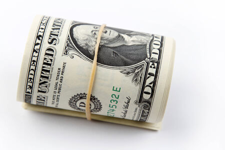 Roll of U.S. banknotes rolled up on plain background