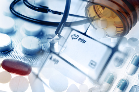 Stethoscope and pills on keyboardの写真素材