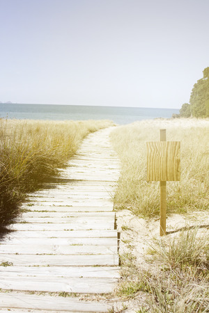 Boardwalk trail and blank sign at beachの写真素材