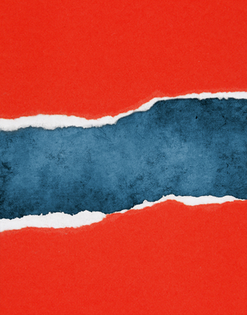 Hole ripped in red paper on blue background. Copy spaceの写真素材