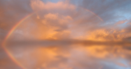 Rainbow in fluffy clouds sky の写真素材