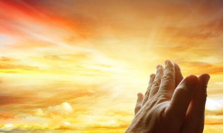 Hands together praying in bright sky