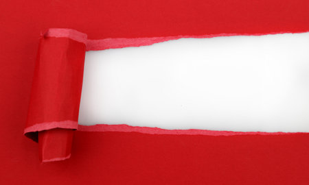 Hole ripped in red paper on white backgroundの写真素材