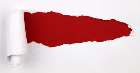 Hole ripped in white paper on red backgroundの写真素材