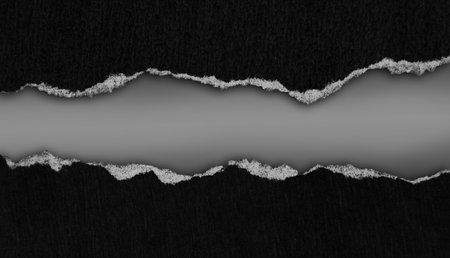 Ripped black paper on grey backgroundの写真素材