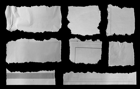 Eight pieces of torn newspaper on black backgroundの写真素材
