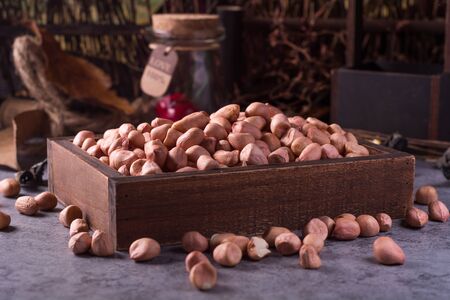 close up of raw peanuts or arachis in ceramic bowl on wood background