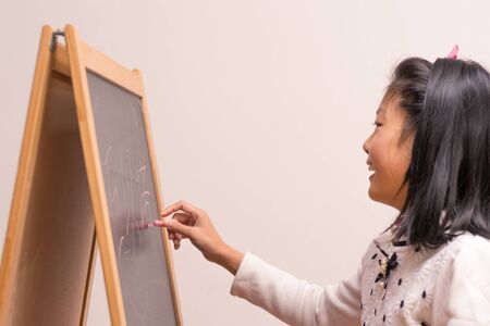 A chinese girl writing on dark blackboard backgroundの写真素材
