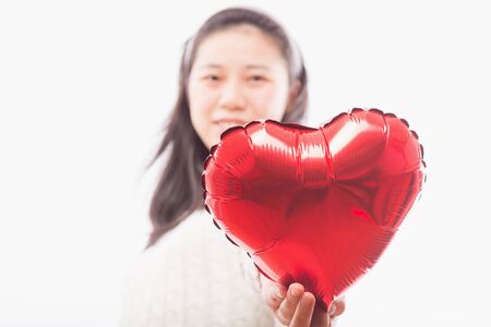Beautiful young woman with heart shape air balloon on color background. Woman on Valentine's Day. Symbol of loveの写真素材
