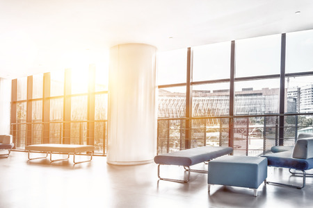 Office in a loft style with white brick walls and concrete columns. There is a meeting zone with a large wooden table with gray chairs and glass partitions.のeditorial素材