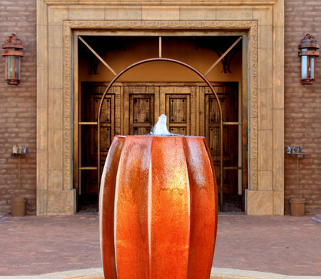 Courtyard fountain and an archway that leads to a giant wooden door and the entrace to this beautiful churchの写真素材