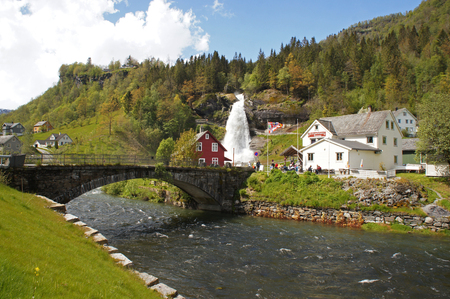 Steinsdalsfossen waterfall in the river of steine ??- scenic landscape with cascade surounded by mountains and traditional norwegian, scandinavian housesの写真素材