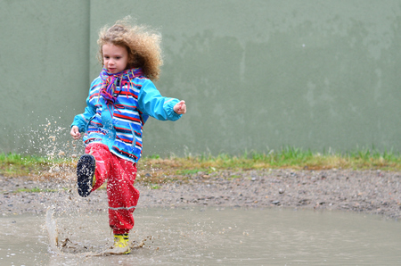 Little boy with many curls plays in a puddleの写真素材