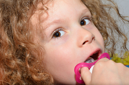 Little boy with long curly hair is having fun making faces