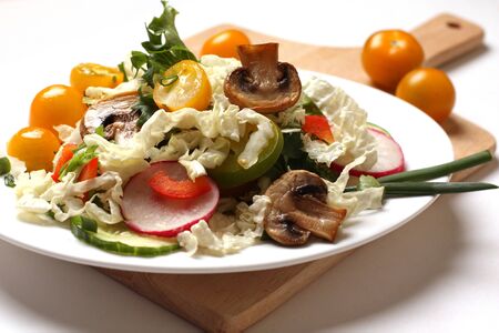 plate of salad with vegetables, herbs and mushrooms on a tableの写真素材