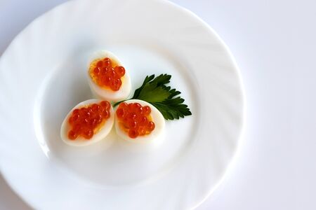 Red caviar. Sandwich with red caviar and quail egg. White background, white plate. Copy spaceの写真素材