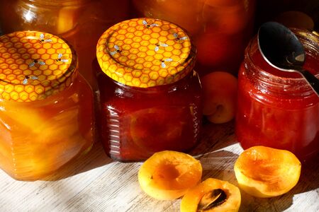Jars with apricot and plum jam on a wooden background. Bright Sunlightの写真素材