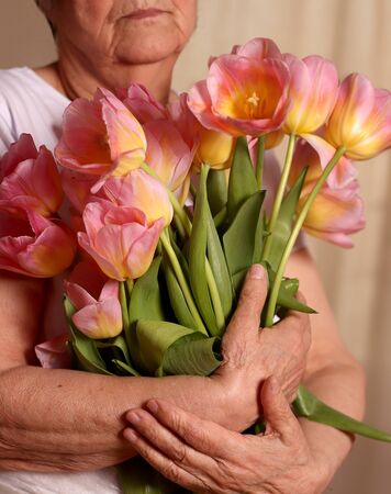 Hands of a senior woman holding flower bouquet. Idea of a mother's day greeting card, women's day or grandmothers day. Older Persons Dayの写真素材