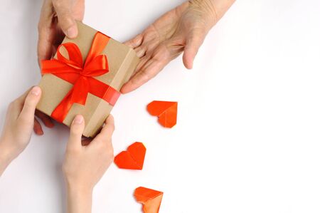 Child with love makes a gift to the grandmother. Box of red tapeの写真素材
