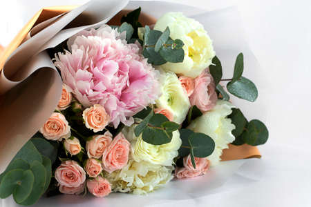 A beautiful bouquet of mixed flowers. The concept of a flower shop, flower Delivery. Close-up of a bouquet of peonies and roses on a light backgroundの写真素材