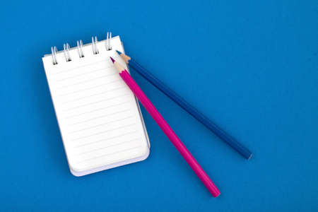 Empty open Notepad, business template layout for adding your design. Top view of a spiral Notepad and pencil on a blue background. school notebook for notes. Copy space.の写真素材