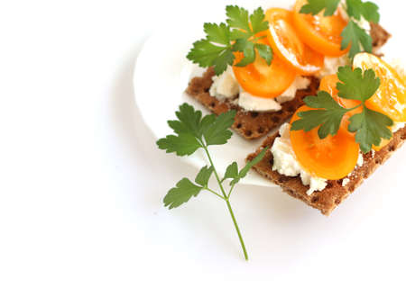 Light Breakfast, healthy food. Crusty bread with soft cottage cheese, tomatoes and parsley.The sandwich is on a white plate, isolated on a white backgroundの写真素材