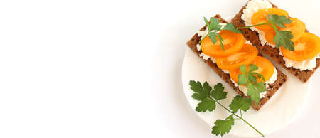Light Breakfast, healthy food. Crusty bread with soft cottage cheese, tomatoes and parsley.The sandwich is on a white plate, isolated on a white background. Banner, copy spaceの写真素材