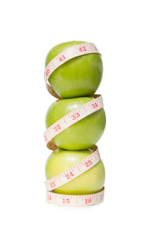 Stacked apples with a tape measure, isolated on white backgroundの写真素材