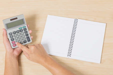 hand press calculator and notebook on wood tableの写真素材
