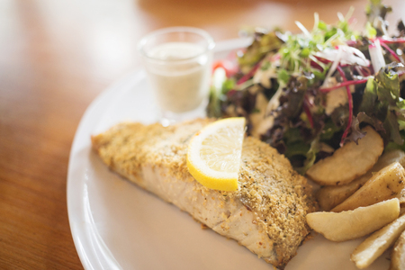 Roast fish steak fresh with potato and fresh vegetable salad on white plateの写真素材