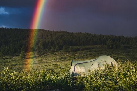 Tourist tent under the rainbow in the Ongudaysky district of the Altai republic, Russia