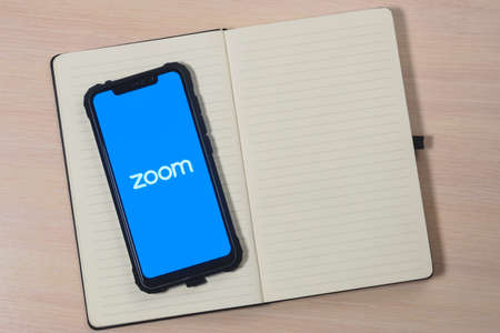 Zoom app logo on the screen smartphone. Zoom Video Communications is a company that provides remote conferencing services. Preparing for an online meeting.のeditorial素材