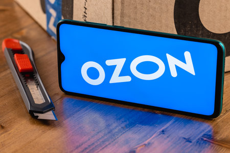 Ozon logo on the screen smartphone closeup. Ozon is one of the first e-commerce companies in Russia. Smartphone on the background of the parcel and box cutter.のeditorial素材