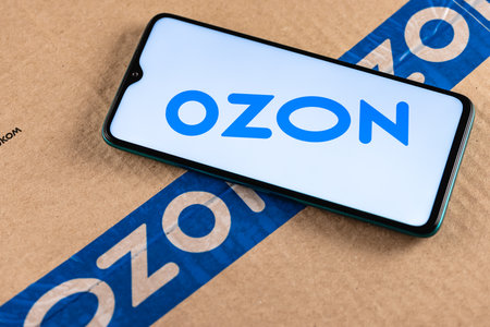 Ozon logo on the screen smartphone closeup. Ozon is one of the first e-commerce companies in Russia. Smartphone on the background of the parcel.のeditorial素材