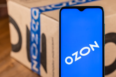 Ozon logo on the screen smartphone closeup. Ozon is one of the first e-commerce companies in Russia. Smartphone on the background of the parcel.のeditorial素材