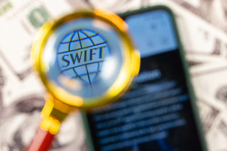 Kazan, Russia - May 4, 2021: SWIFT is Society for Worldwide Interbank Financial Telecommunication network. SWIFT on smartphone screen under the magnifying glass.のeditorial素材