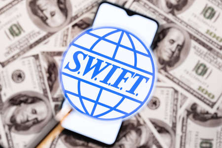 Kazan, Russia - May 4, 2021: SWIFT is Society for Worldwide Interbank Financial Telecommunication network. SWIFT on smartphone screen under the magnifying glass.のeditorial素材