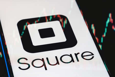 Kazan, Russia - May 30, 2021: Square is a technology company that develops solutions for accepting and processing electronic payments. Square logo on smartphone screen. Stock chart in the reflection.のeditorial素材