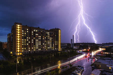 A lightning strike during a thunderstorm against the background of a city building. Night city traffic.の写真素材