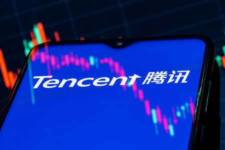 Kazan, Russia - August 4, 2021: Tencent Holdings Ltd. is a Chinese multinational technology conglomerate holding company. A smartphone with the Tencent logo on the background of the stock chart.のeditorial素材