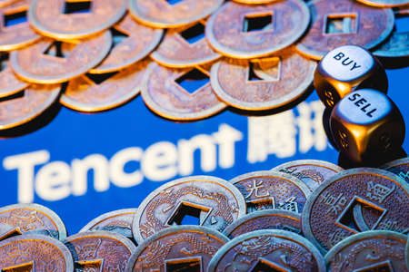 Kazan, Russia - August 4, 2021: Tencent Holdings Ltd. is a Chinese multinational technology conglomerate holding company. Dices with the words SELL BUY. The Tencent logo and Feng Shui coins.のeditorial素材