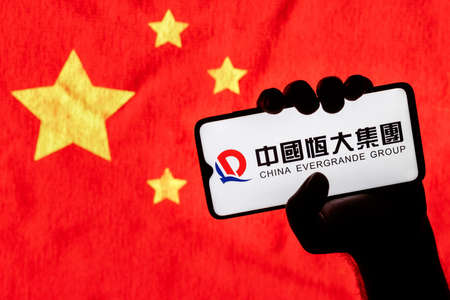 Kazan, Russia - September 22, 2021: The Evergrande Group is the second largest property developer in China by sales. A smartphone with the Evergrande logo in a clenched hand.のeditorial素材