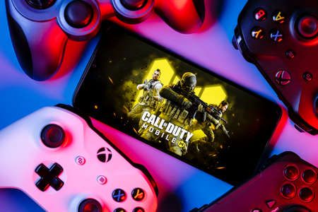 Kazan, Russia - September 07, 2021: Call of Duty: Mobile is a free-to-play shooter game. A smartphone with the frame from Call of Duty on the screen surrounded by gamepads.のeditorial素材