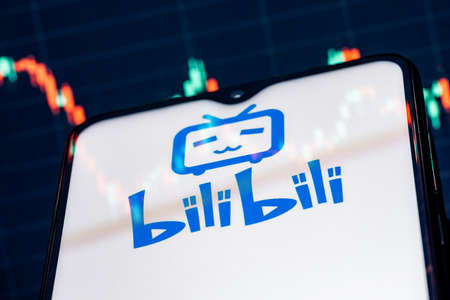 Kazan, Russia - August 23, 2021: Bilibili is a Chinese video sharing website themed around animation, comics, and games. A smartphone with the Bilibili logo on the background of the stock chart.のeditorial素材