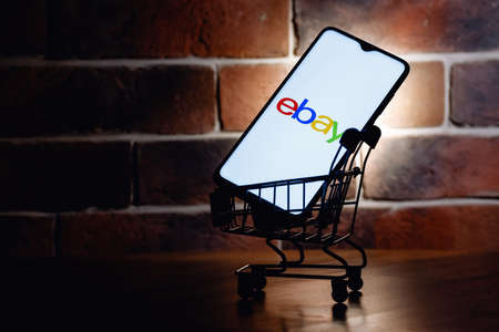 Kazan, Russia - Sep 25, 2021: eBay is an e-commerce corporation that offers online shopping, auction and marketplace services. Smartphone with eBay logo on screen in the shopping cart.のeditorial素材