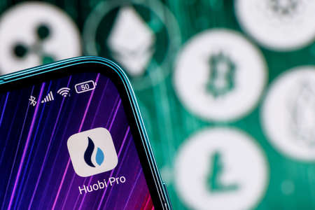 Kazan, Russia - Oct 05, 2021: Huobi is a cryptocurrency exchange. Huobi app on smartphone screen against the background of the main cryptocurrencies.のeditorial素材